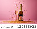 Champagne bottle on pink background with golden glitter on pink background. 129388922