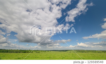 An Expansive Green Landscape Featuring Dynamic Clouds in the Bright Blue Sky Above 129389540