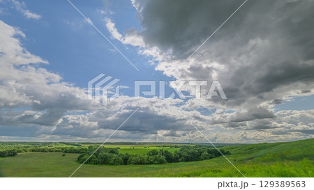 A beautiful scenic landscape featuring dramatic clouds and lush, vibrant green fields 129389563