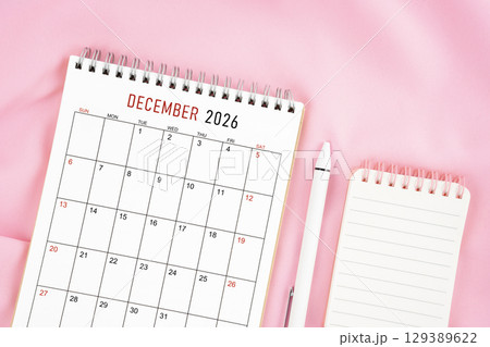 December 2026 month calendar and pen with open diary on pink color fabric background. Monthly calendar concept. 129389622
