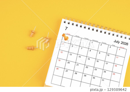 July 2026 Monthly desk calendar for 2026 year with wooden pin on yellow background. 129389642