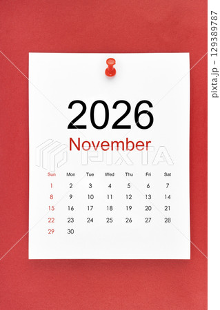 November 2026 calendar page with push pin on red color background. 129389787