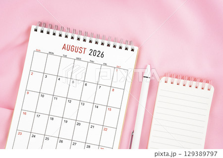 August 2026 month calendar and pen with open diary on pink color fabric background. 129389797