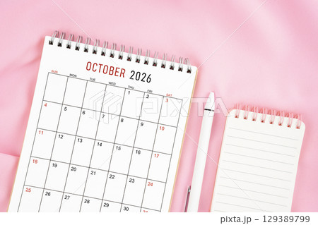 October 2026 month calendar and pen with open diary on pink color fabric background. October 2026 month calendar and pen with open diary on pink color fabric background. 129389799