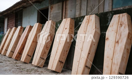 Rustic wooden coffins stacked against old building wall 129390726