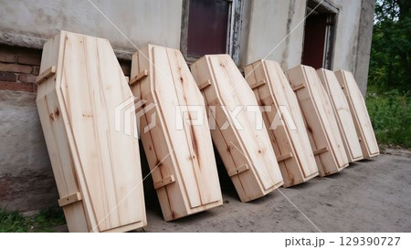 Plain wooden coffins leaning outside an old rural building 129390727