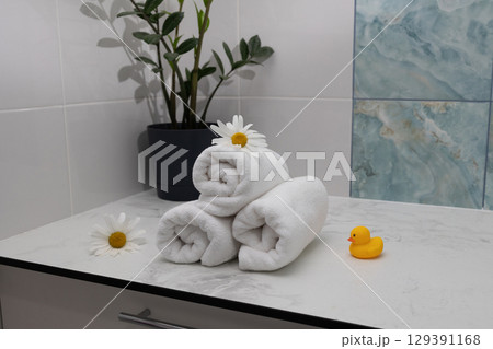 Towel Arrangement With Flowers and Rubber Duck in a Serene Bathroom Setting Towel Arrangement With Flowers and Rubber Duck in a Serene Bathroom Setting 129391168