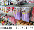Close up of purple makeup brush sets neatly displayed on a store shelf alongside various cosmetic products.   129391476