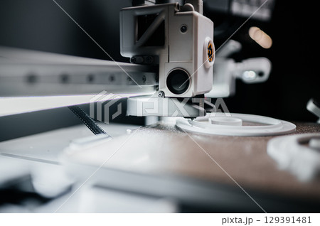 Hands of young engineer adjusting 3D printer to print resin figures 129391481