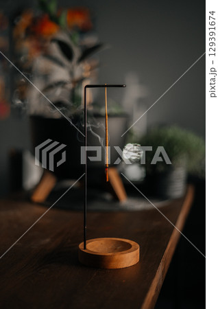 Incense stick smoldering in holder, burning candles, dry flowers and Tibetan singing bowl on wooden table outdoors Incense stick smoldering in holder, burning candles, dry flowers and Tibetan singing bowl on wooden table outdoors 129391674