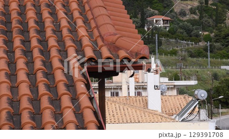 Close up view of terracotta roof tiles on Mediterranean villa overlooking beautiful landscape and greenery, capturing architectural details and rustic charm of traditional design Close up view of terracotta roof tiles on Mediterranean villa overlooking beautiful landscape and greenery, capturing architectural details and rustic charm of traditional design 129391708