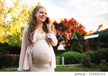 Joyful expecting mother enjoying a sunny day outdoors 129392533