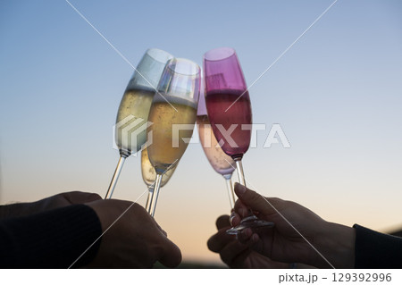Celebration with champagne flutes at sunset among friends, toasting the moment and enjoying the 129392996