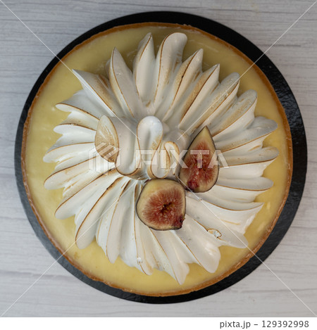 Sunny and Bright Orange Lemon Citrus Meringue Pie on a black plate on white background 129392998