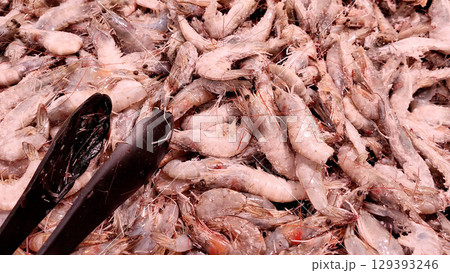 A pile of fresh raw frozen shrimps prawns sold in a supermarket. Seafood background 129393246