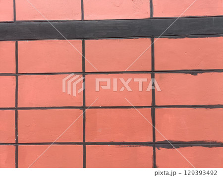 Close up of brick wall with black mortar lines, showing pattern of rectangular bricks painted reddish orange color, with some slight imperfections Close up of brick wall with black mortar lines, showing pattern of rectangular bricks painted reddish orange color, with some slight imperfections 129393492