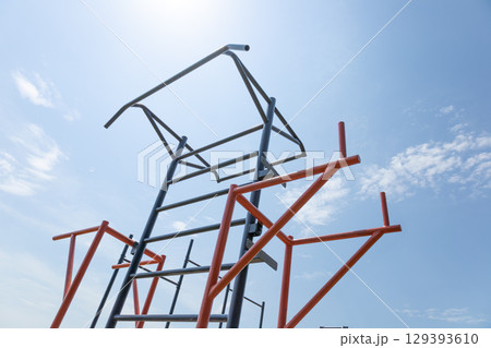 Bright sunlight shines on outdoor fitness equipment, featuring various bars and structures ideal for strength training and exercise Bright sunlight shines on outdoor fitness equipment, featuring various bars and structures ideal for strength training and exercise 129393610