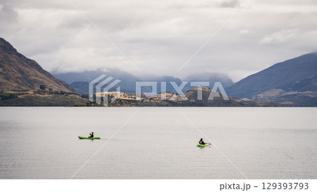 Kayakers kayaking on an alpine lake on a cloudy day, New Zealand 129393793