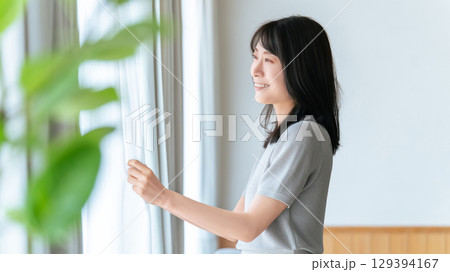 カーテンを開ける女性 129394167