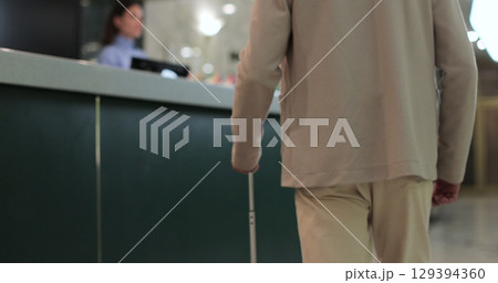 Close up. Businessman arriving in business trip with suitcase at hotel front desk. Man with luggage checking in. Travel and reception desk concept. Close up. Businessman arriving in business trip with suitcase at hotel front desk. Man with luggage checking in. Travel and reception desk concept. 129394360