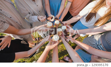 Group of school friends enjoying ice cream cones and chocolate bars together in a sunny day 129395170