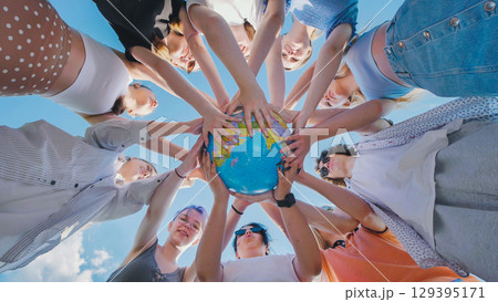 Students holding a globe, symbolizing global citizenship, environmental awareness, and international cooperation for a sustainable future 129395171