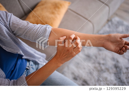 Woman scratching her itchy arm, suffering from dermatitis at home 129395229
