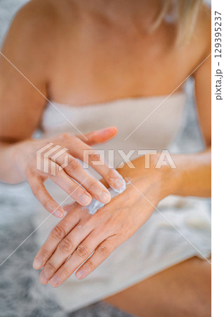 Woman applying moisturizing cream on her hands after shower Woman applying moisturizing cream on her hands after shower 129395237