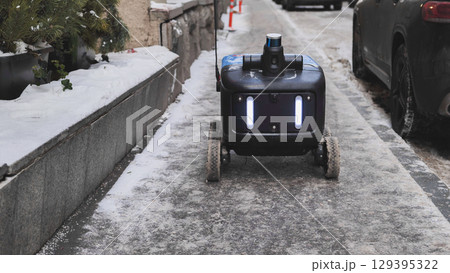 Autonomous delivery robot moving on a snowy sidewalk in Moscow. 129395322