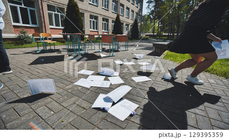 Students celebrate the end of the school year by tossing their exam papers in the air 129395359