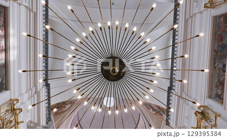 Large round chandelier illuminating church interior 129395384