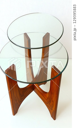 A wooden table with two glass tops and a wooden base 129395883