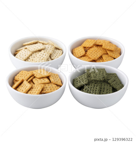 Four white bowls filled with assorted crackers different colors, including white, orange, brown, and green, are arranged square pattern. crackers are neatly stacked, showcasing variety of flavors 129396322