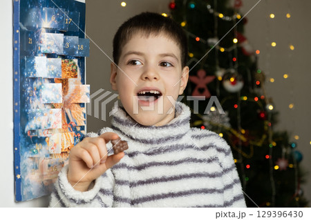 A happy child took out chocolate from the advent calendar. Preparing for Christmas A happy child took out chocolate from the advent calendar. Preparing for Christmas 129396430