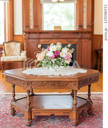 Wooden table with a vase of flowers on top of it 129396551
