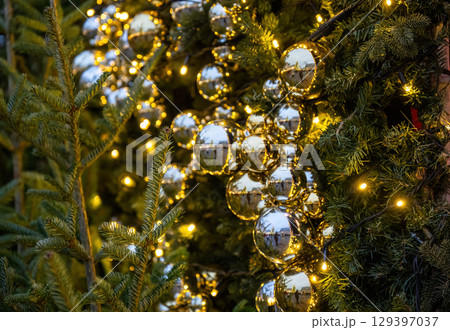 Close-up of Christmas tree decorated with shiny golden baubles and festive lights 129397037