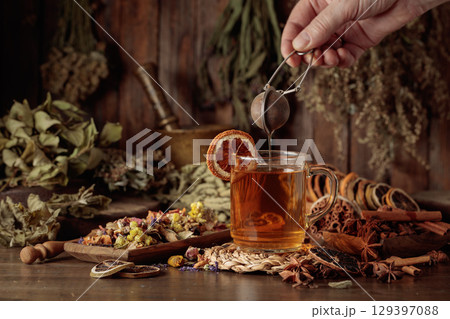 Cup of herbal tea with various dried herbs, flowers, and spices. 129397088