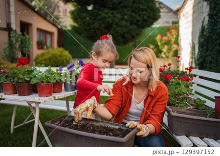 Mother and daughter gardening together in their backyard 129397152