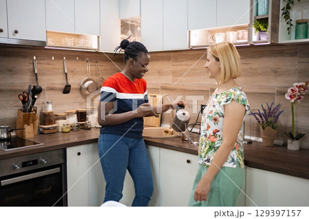 Two friends enjoy coffee preparation in a bright modern kitchen Two friends enjoy coffee preparation in a bright modern kitchen 129397157