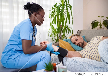 Caring nurse provides foot treatment to patient at home 129397172