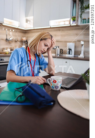 Exhausted doctor having a headache after working on a laptop at home Exhausted doctor having a headache after working on a laptop at home 129397201