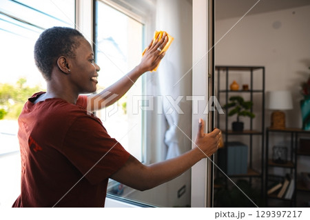 Young Woman Cleaning Windows in her Modern Apartment Young Woman Cleaning Windows in her Modern Apartment 129397217