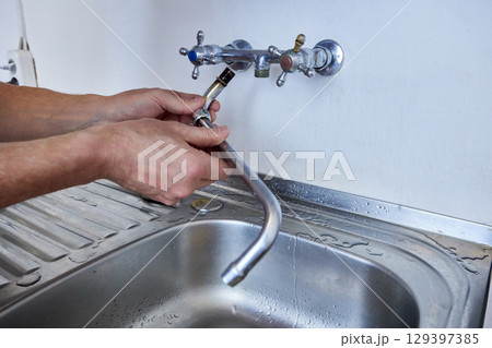 Removal of long spout from wall-mounted kitchen faucet, showing direct connection between faucet body and spout. Removal of long spout from wall-mounted kitchen faucet, showing direct connection between faucet body and spout. 129397385
