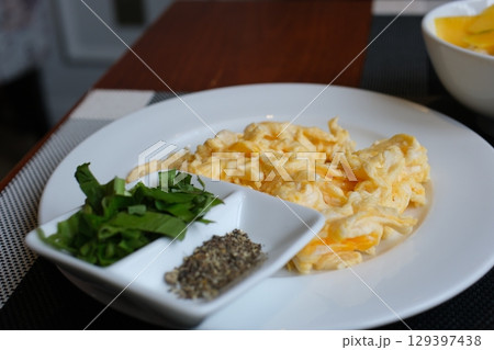 Scrambled Eggs on frying pan for healthy breakfast or brunch, top view, copy space. Homemade meal recipe - scrambled eggs on black background. 129397438