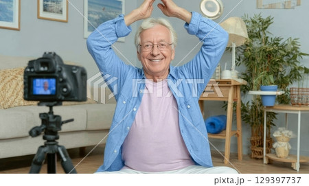 Senior influencer is joyfully vlogging at home, showcasing a relaxed atmosphere with cozy decor and engaging personality for authentic content creation 129397737