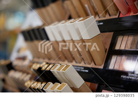 Several bottles of foundation are neatly lined up on a shelf for display 129398035