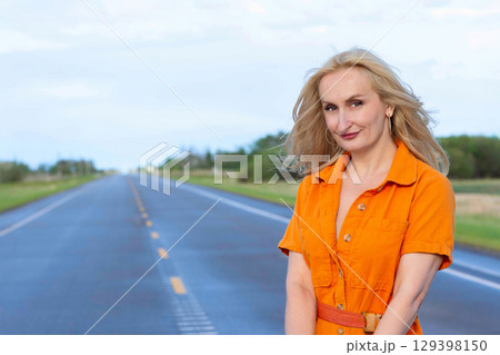 Blonde free woman is on the empty rural road in summer. Blonde free woman is on the empty rural road in summer. 129398150