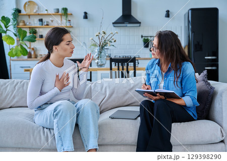 Serious teen girl in session in office of professional psychologist, therapist Serious teen girl in session in office of professional psychologist, therapist 129398290