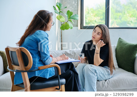 Sad teenage girl student talking with social psychologist, therapist, counselor Sad teenage girl student talking with social psychologist, therapist, counselor 129398299