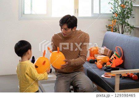Father and Son. Engaging playtime with balloons during festive celebration at home. Father and Son. Engaging playtime with balloons during festive celebration at home. 129398465